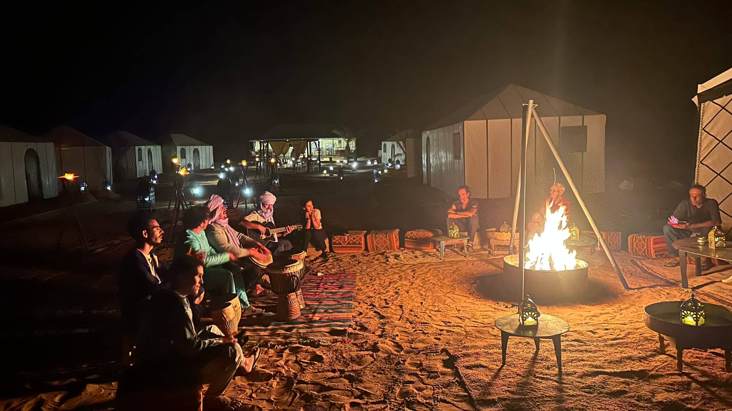 Berber musicians and travelers gathered around a campfire in the Sahara Desert at night