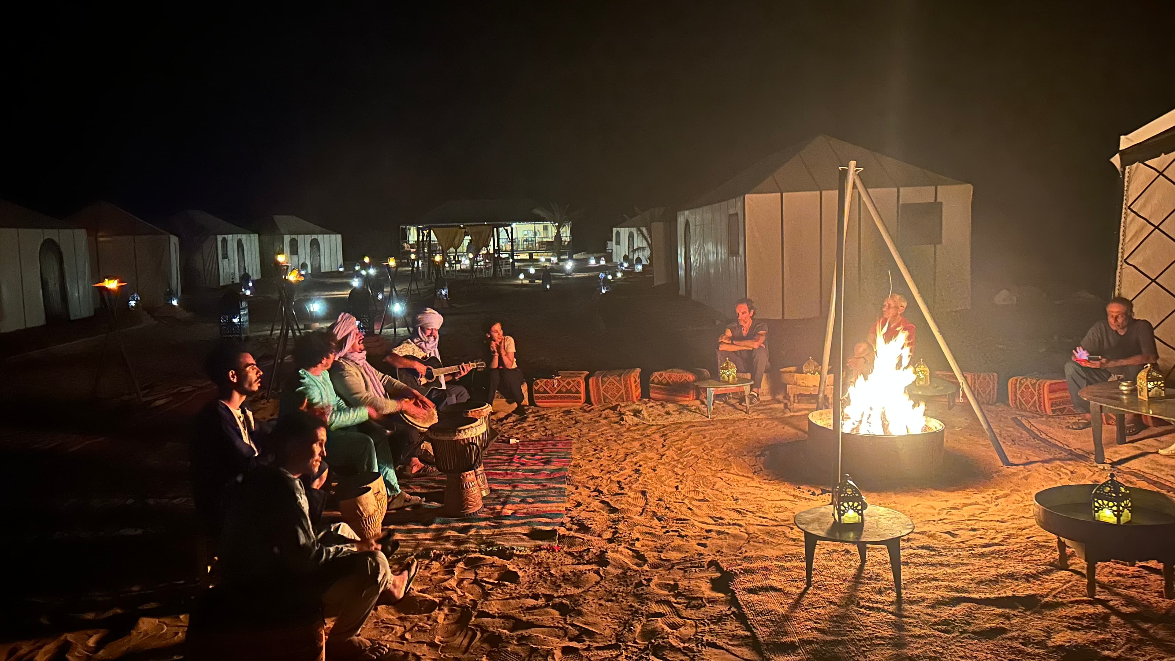 Berber musicians and travelers gathered around a campfire in the Sahara Desert at night
